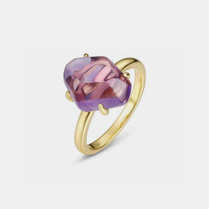 Gold ring with a purple gemstone on a light gray background