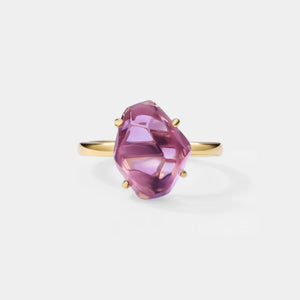 Gold ring with a purple gemstone on a light gray background