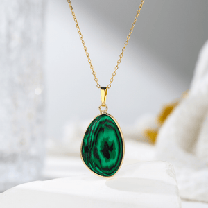 Gold necklace with a green pendant on a soft white background