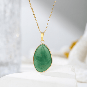 Gold necklace with a green pendant on a white surface