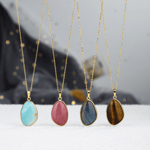 Four gold necklaces with colorful pendant stones on a white surface.