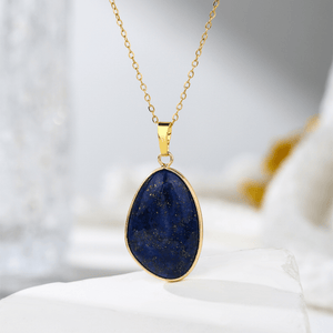 Gold necklace with a blue pendant on a white surface