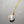 Necklace with a clear crystal pendant on a gold chain against a gray background
