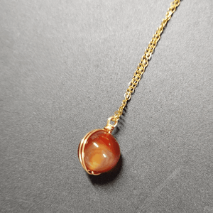 Necklace with a red gemstone pendant on a gray background