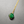 Green jade pendant on a gold chain against a gray background