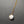 Necklace with a white marbled pendant on a gold chain against a gray background