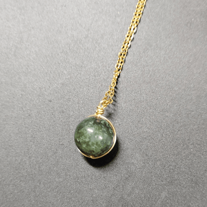 Necklace with a green gemstone pendant on a gray background