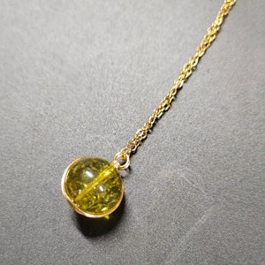 Necklace with a yellow gemstone pendant on a gray background