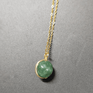 Necklace with a green gemstone pendant on a gray background