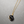 Necklace with a black pendant on a gold chain against a gray background