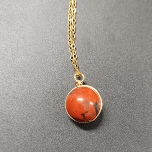 Necklace with a red stone pendant on a gray background