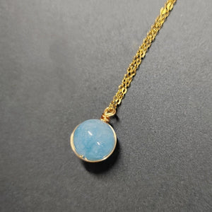 Necklace with a blue pendant and gold chain on a gray background