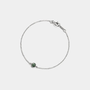 Silver bracelet with a green gemstone on a light gray background