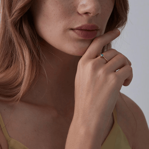 A model wearing a gold bypass ring, featuring a natural opal stone in a thin bypass design.