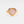 A gold-colored cocktail ring with a rose quartz crystal, set on a plain white background.