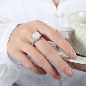 A gold-colored cocktail ring with a raw rose quartz crystal set on a rock, part of a collection.