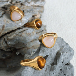 Gold rings with gemstones on a textured stone surface