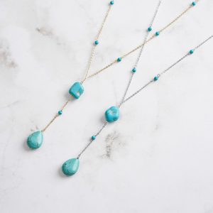 Two turquoise bead necklaces on a marble surface