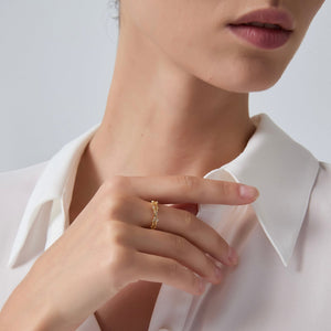 Close-up of a person wearing a gold ring on a plain background