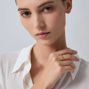 Close-up of a person wearing a gold ring on a plain background