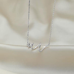 Silver necklace with a delicate design on a beige fabric background