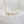 Gold necklace with a wavy design on a white background