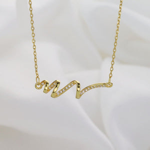Gold necklace with a wavy design on a white background