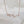 Rose gold necklace with a wavy design on a soft white background