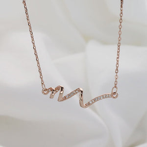 Rose gold necklace with a wavy design on a soft white background