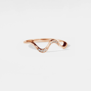 A gold-colored stacking ring with a wavy design and small white stones embedded on one side, displayed against a white background.