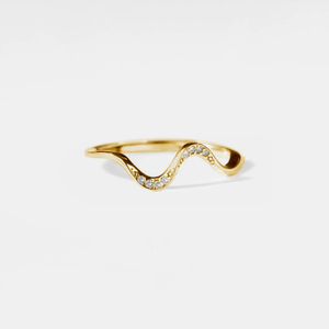 Gold ring with a wavy design and small diamonds on a light gray background