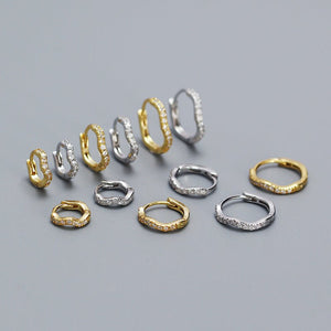 Set of gold and silver hoop earrings on a gray background