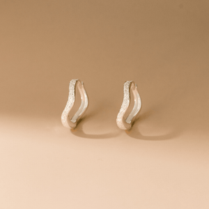 Pair of gold hoop earrings on a beige background