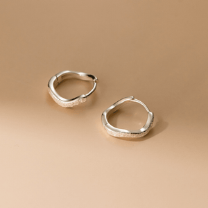 Pair of silver hoop earrings on a beige background