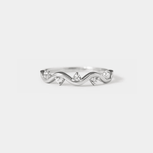 A gold-colored stacking band ring with wave design and small cubic zirconia stones.