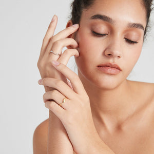 A model wearing gold and silver stacking rings with curved wave design, displayed on a plain background.