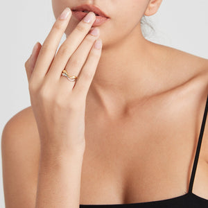 A model wearing gold and silver stacking rings with curved wave design, displayed on a plain background.
