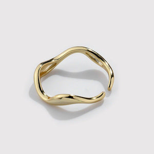 A gold stacking ring with curved wave design, displayed on a plain background.