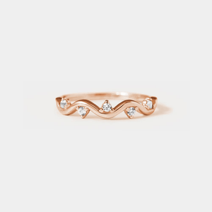 A gold-colored stacking band ring with wave design and small cubic zirconia stones.