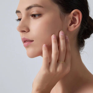 Woman touching her neck with one hand against a light gray background