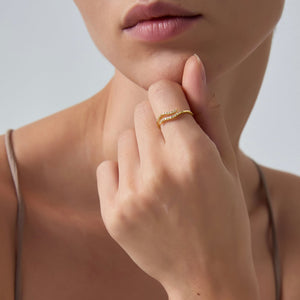 Close-up of a hand wearing a gold ring with a blurred background