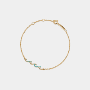 Gold bracelet with turquoise stones on a light beige background