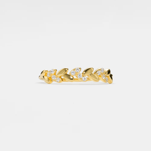 Gold ring with leaf design and embedded diamonds on a light gray background