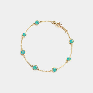 Gold bracelet with turquoise stones on a light gray background