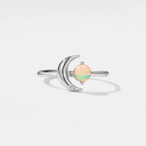 Silver ring with a crescent moon design and opal stone on a light gray background