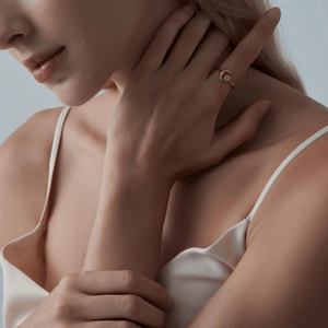 Model wearing a gold ring with a crescent moon design and opal stone on a light gray background