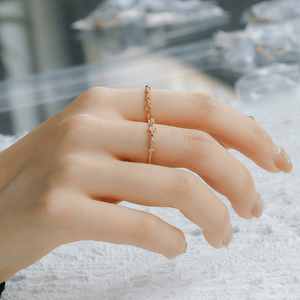Hand wearing a gold ring with small stones on a blurred background