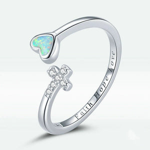 Silver ring with heart-shaped opal and cross design on a white background