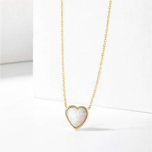 Gold necklace with a heart-shaped opal pendant on a white background
