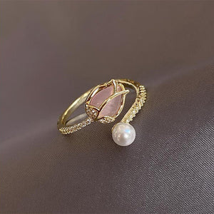 Gold ring with pink gemstone and pearl on a dark fabric background